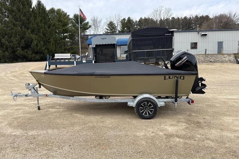 Slide: The Image of 2026 Lund 1675 Alaskan Tiller boat on trailer, covered, with Mercury outboard motor. - 10