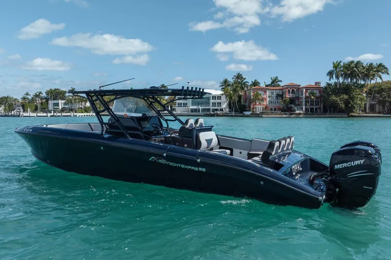 Slide: The Image of 2014 Midnight Express 37 Open boat on turquoise water, with Mercury engines, near luxury waterfront homes. - 3