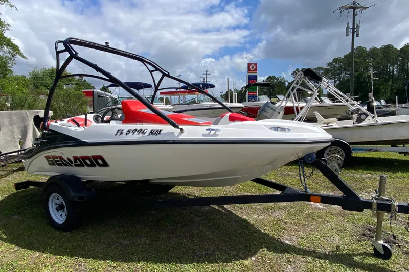 The Image of 2007 Seadoo 150 Speedster boat on trailer, parked outdoors under cloudy sky. - 1