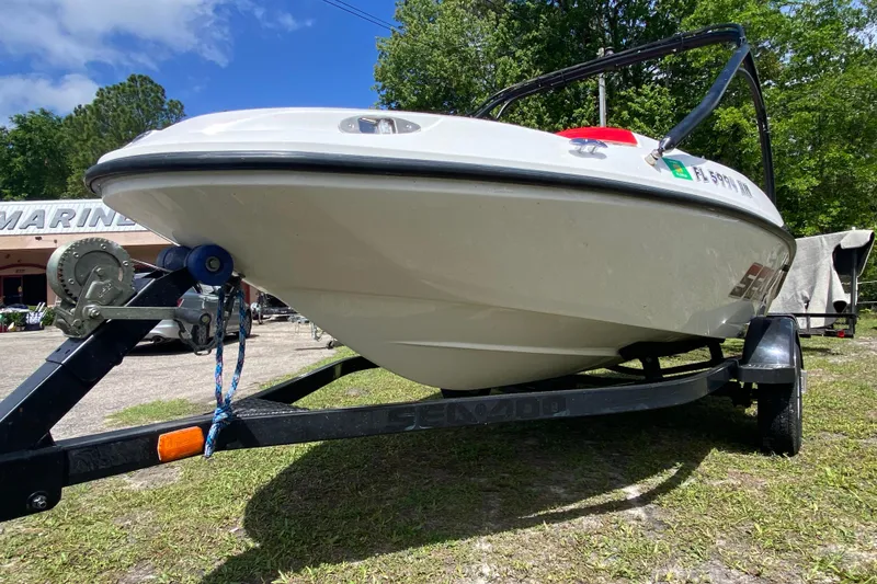 Slide: The Image of 2007 Seadoo 150 Speedster boat on trailer, parked outdoors near a marine shop. - 10