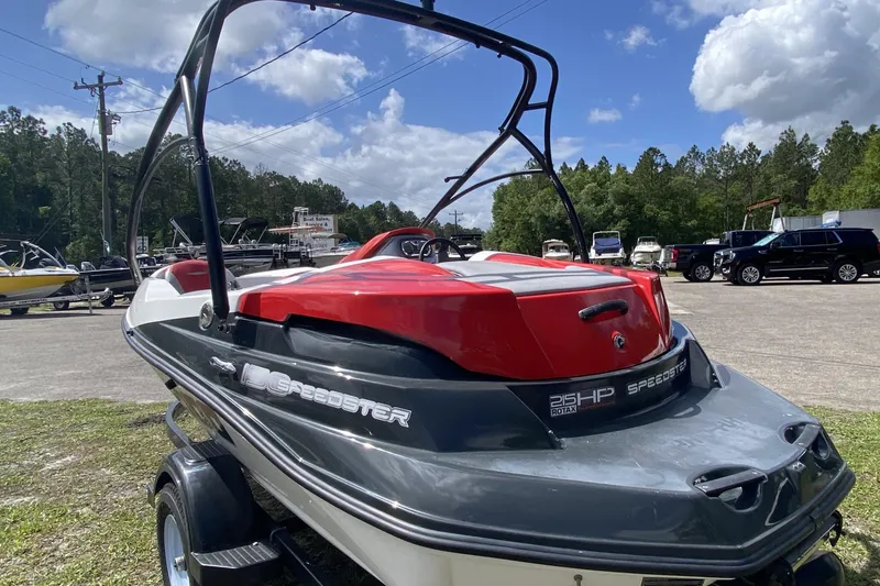 Slide: The Image of 2007 Seadoo 150 Speedster boat with red and black design, parked outdoors under a blue sky. - 3