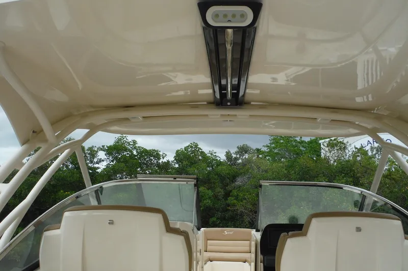 Slide: The Image of 2017 Scout 255 Dorado boat interior with canopy and seating, surrounded by greenery. - 32