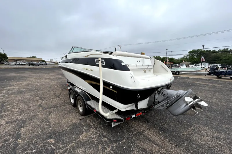 Slide: The Image of 2001 Crownline 239 DB boat on trailer, parked in a lot under cloudy skies. - 5