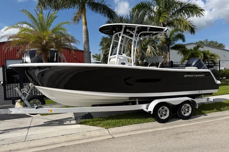 The Image of 2016 Sportsman Heritage 231 Center Console boat on trailer, parked near palm trees. - 1