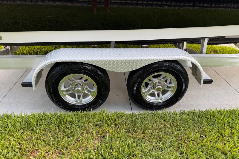 Slide: The Image of Trailer wheels of a 2016 Sportsman Heritage 231 Center Console boat on grass. - 18