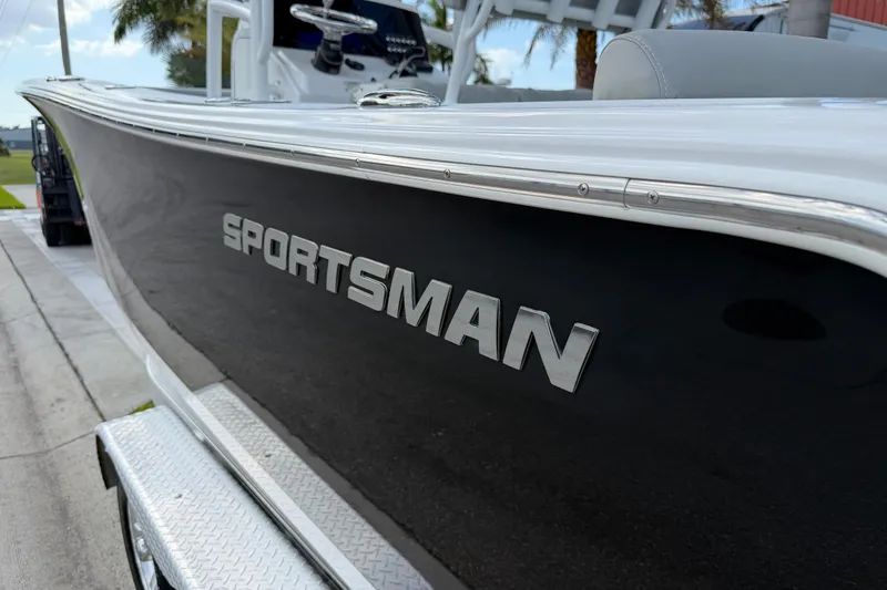 Slide: The Image of 2016 Sportsman Heritage 231 Center Console boat, sleek black hull, parked on trailer. - 25