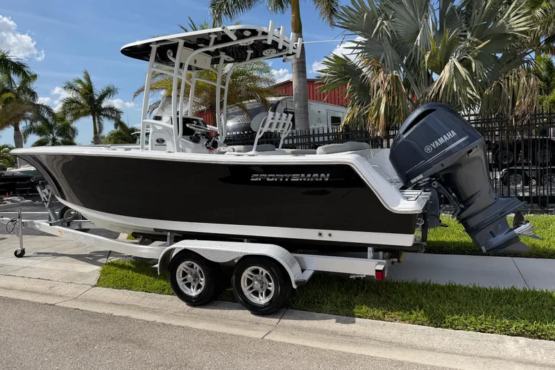 Slide: The Image of 2016 Sportsman Heritage 231 Center Console boat on trailer, parked near palm trees. - 3