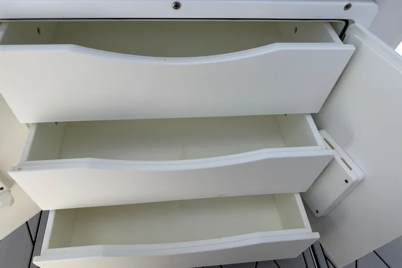 Slide: The Image of Open white storage drawers on a 2016 Sportsman Heritage 231 Center Console boat. - 62