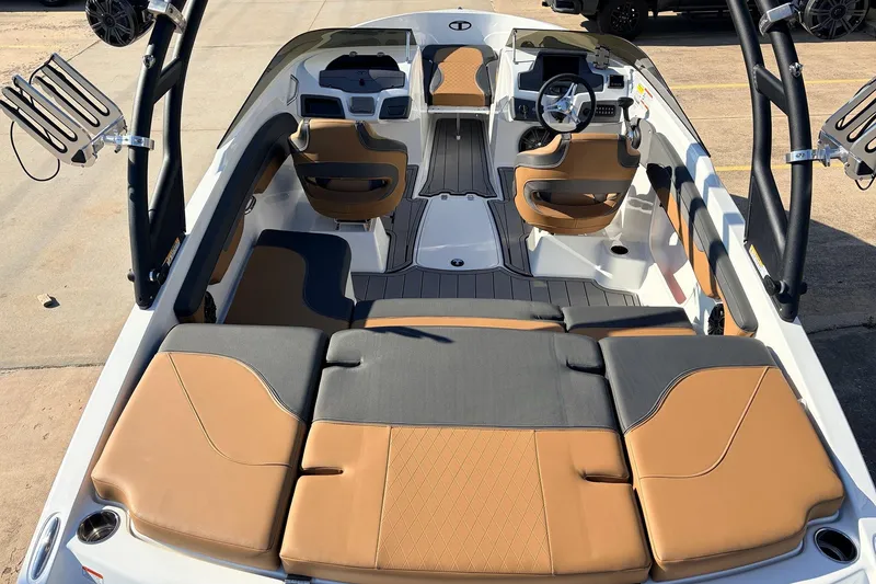 Slide: The Image of 2025 Tahoe 210 Si boat interior with tan and gray seating, modern dashboard, and wakeboard racks. - 11