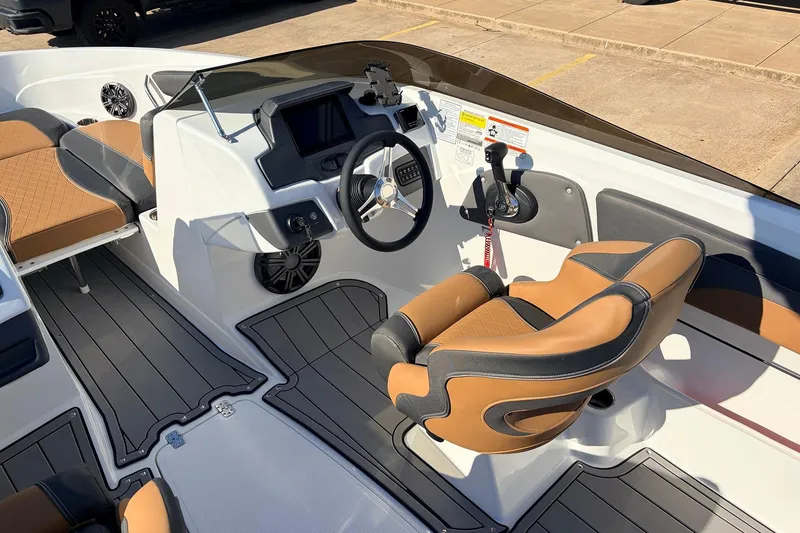 Slide: The Image of 2025 Tahoe 210 Si boat interior with tan and black seating, modern dashboard, and steering wheel. - 31