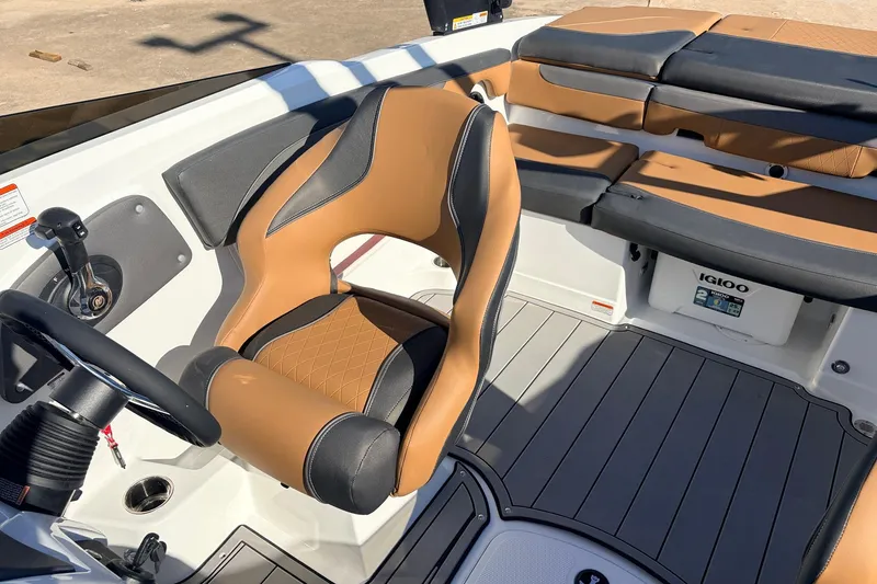 Slide: The Image of 2025 Tahoe 210 Si boat interior with tan and black seating, steering wheel, and Igloo cooler. - 37