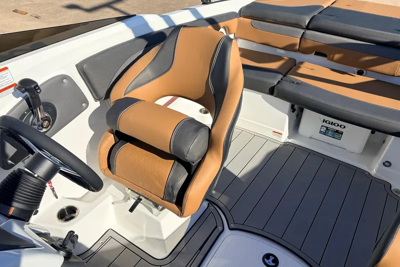 Slide: The Image of 2025 Tahoe 210 Si boat interior with tan and black seating, steering wheel, and Igloo cooler. - 38