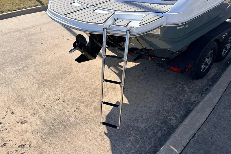 Slide: The Image of 2025 Tahoe 210 Si boat with ladder on trailer, parked on concrete surface. - 8
