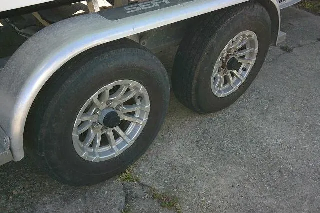 Slide: The Image of Trailer wheels for 2022 Sea Pro 259 Center Console boat on pavement. - 17
