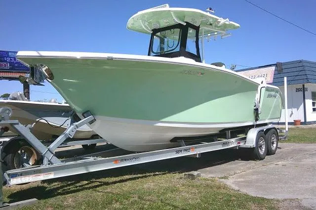 Slide: The Image of 2022 Sea Pro 259 Center Console boat on trailer, light green hull, parked outdoors. - 2