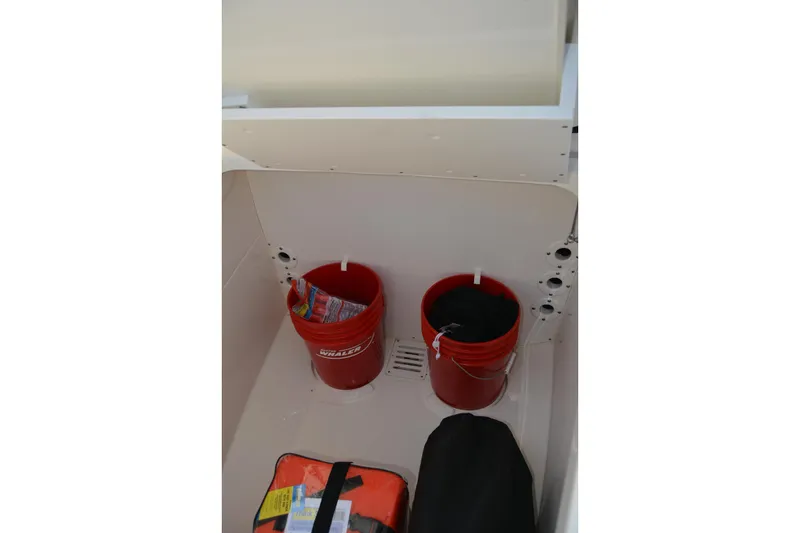Slide: The Image of Storage area on a 2021 Boston Whaler 270 Dauntless with red buckets and gear. - 24