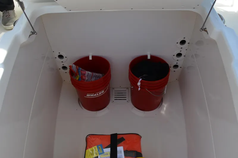 Slide: The Image of Storage area of 2021 Boston Whaler 270 Dauntless with red buckets and safety gear. - 25
