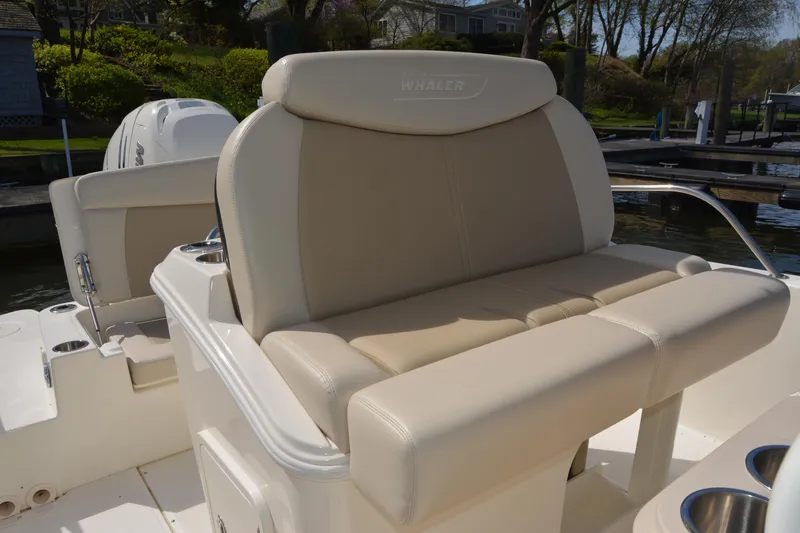 Slide: The Image of 2021 Boston Whaler 270 Dauntless boat with beige seating, docked near lush greenery. - 32