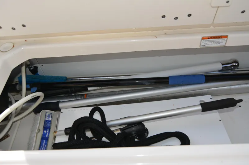 Slide: The Image of Storage compartment of 2021 Boston Whaler 270 Dauntless with cleaning tools and ropes. - 55