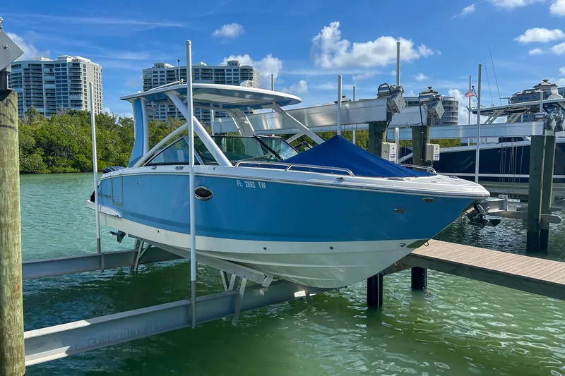 The Image of 2023 Chaparral 280 OSX boat docked at marina with modern buildings in background. - 0