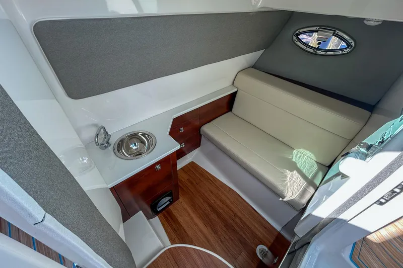 Slide: The Image of 2023 Chaparral 280 OSX cabin interior with seating, sink, and wood flooring. - 11