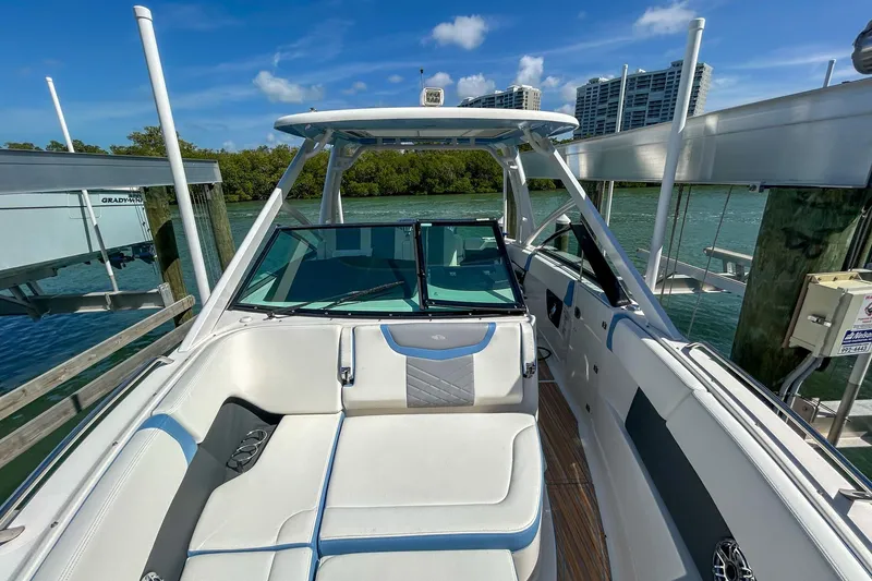 Slide: The Image of 2023 Chaparral 280 OSX boat interior with white seating, docked by the water. - 14