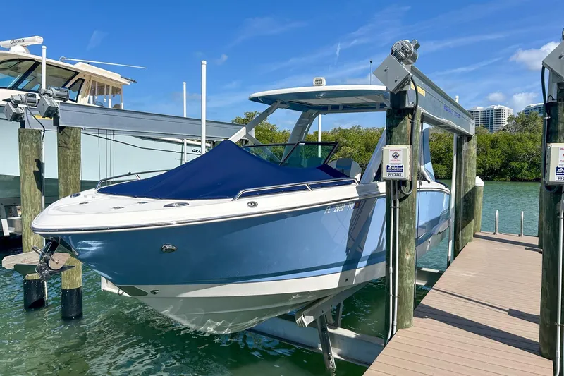 Slide: The Image of 2023 Chaparral 280 OSX boat docked on a lift, blue hull, sunny day. - 2