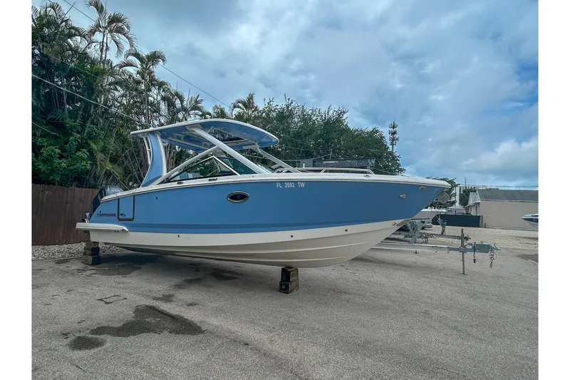 Slide: The Image of 2023 Chaparral 280 OSX boat in blue, parked outdoors under a cloudy sky. - 3