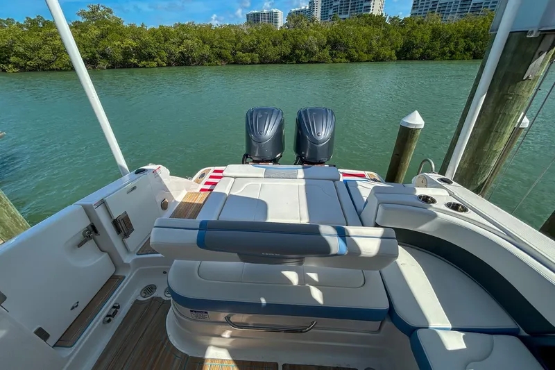 Slide: The Image of 2023 Chaparral 280 OSX boat with dual engines docked by lush greenery. - 8