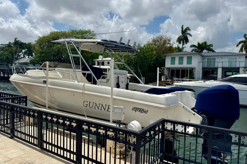 The Image of 2001 Intrepid 339 Walkaround boat docked by waterfront homes under cloudy sky. - 1