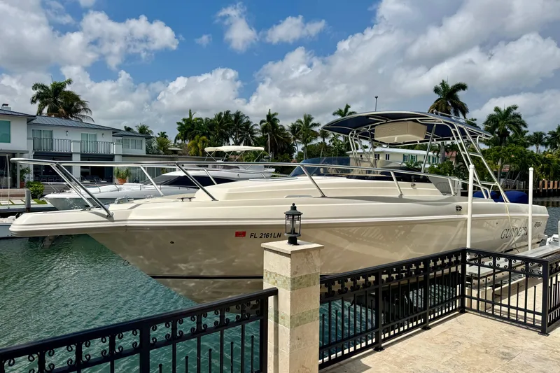 Slide: The Image of 2001 Intrepid 339 Walkaround boat docked by waterfront homes under a cloudy sky. - 2