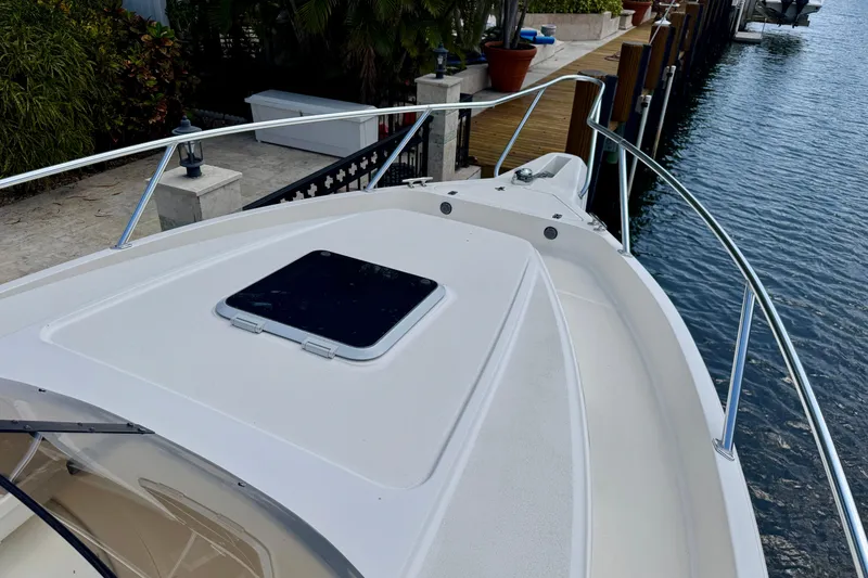 Slide: The Image of 2001 Intrepid 339 Walkaround boat docked by waterfront with lush greenery. - 23