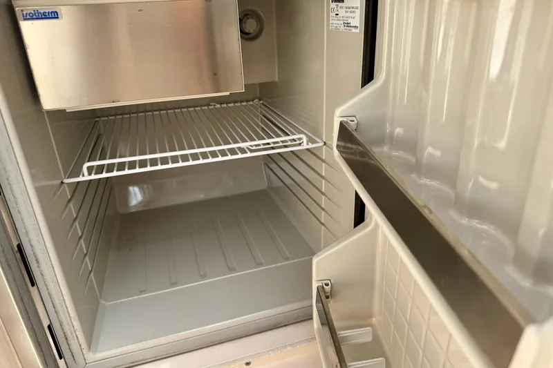 Slide: The Image of Empty refrigerator inside a 2001 Intrepid 339 Walkaround boat, featuring wire shelving. - 33