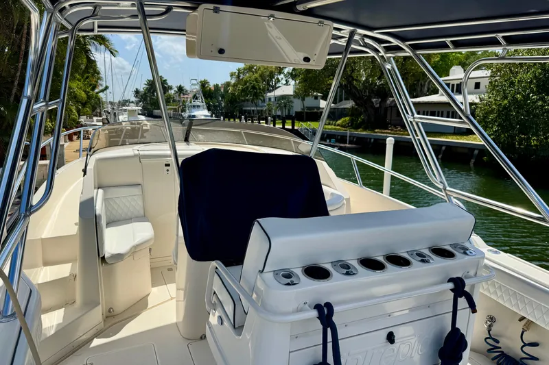 Slide: The Image of 2001 Intrepid 339 Walkaround boat interior with seating and rod holders, docked by a canal. - 48