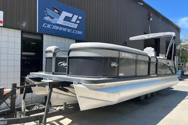 The Image of 2020 Manitou 25 OASIS SL VP pontoon boat on trailer outside marine shop. - 0