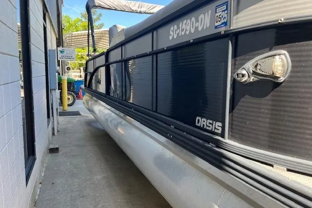 Slide: The Image of 2020 Manitou 25 OASIS SL VP pontoon boat docked beside a building. - 4