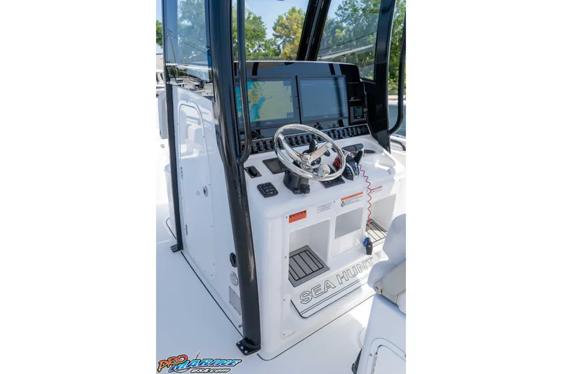 Slide: The Image of 2025 Sea Hunt Gamefish 28 boat console with steering wheel and navigation screens. - 17