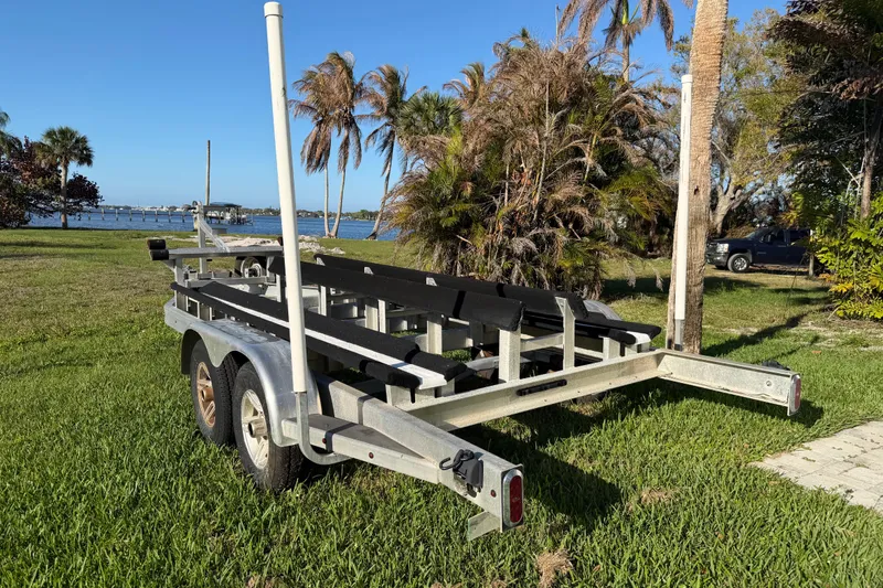 Slide: The Image of Boat trailer on grass near water, surrounded by palm trees, clear blue sky. - 63
