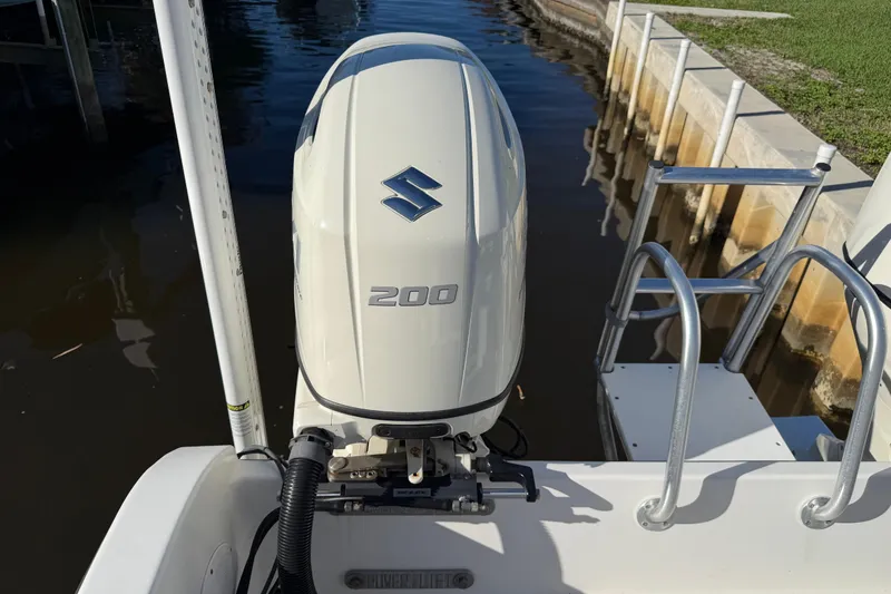 Slide: The Image of Outboard motor on a 2020 Tideline 235 Hybrid boat, docked by water. - 7