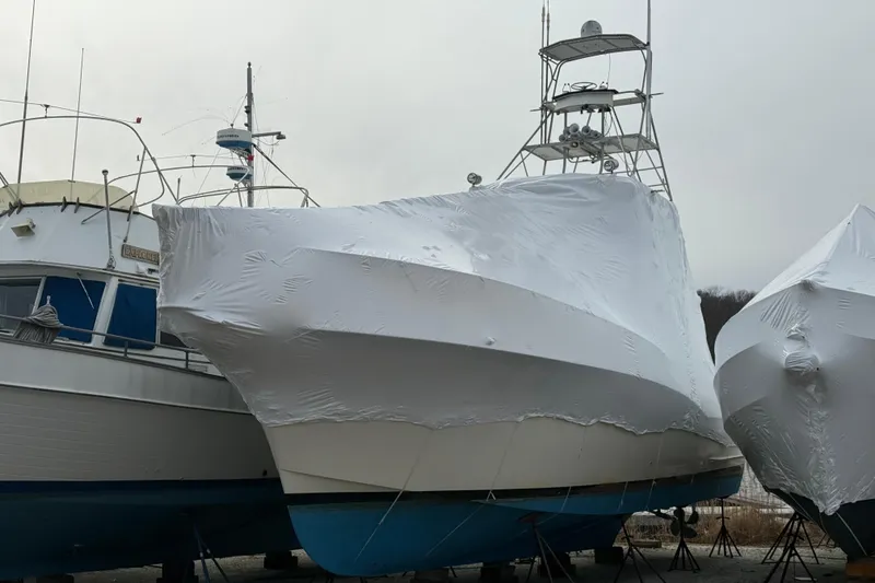Slide: The Image of 1979 Hatteras 46 Convertible boat covered in protective shrink wrap, stored outdoors. - 2