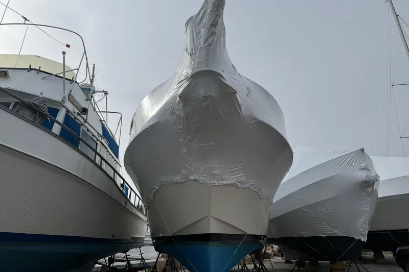 Slide: The Image of 1979 Hatteras 46 Convertible boat covered in protective wrap, docked alongside other boats. - 3