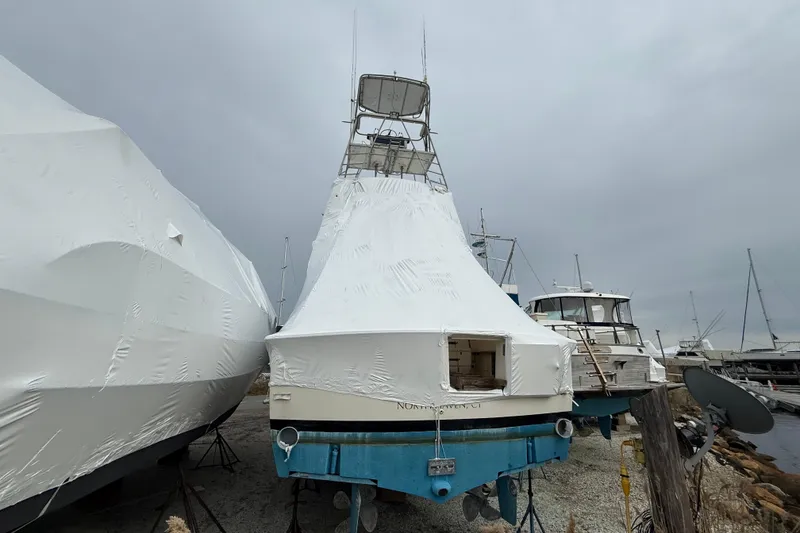 Slide: The Image of 1979 Hatteras 46 Convertible boat covered in protective wrap at a marina. - 4