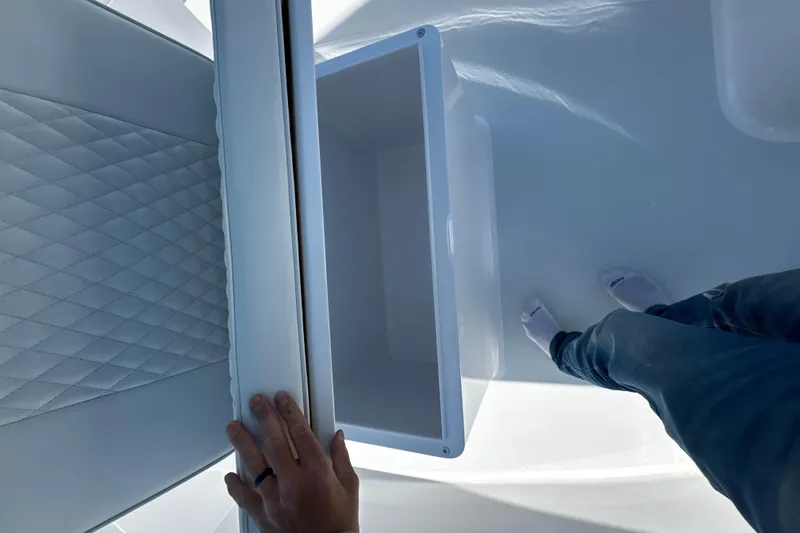 Slide: The Image of Person opening storage compartment on Weaver 25 boat, 2025 model, with quilted upholstery. - 9