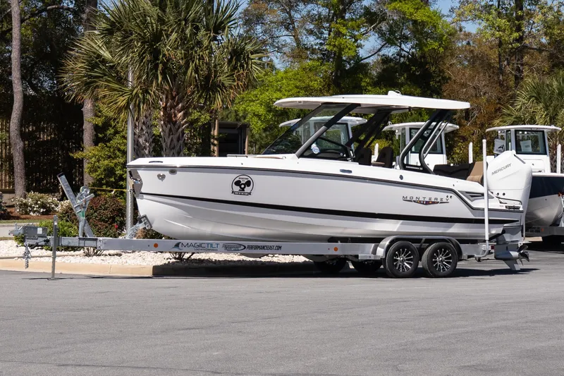 The Image of 2026 Monterey Elite 25 OB boat on trailer, parked outdoors with trees in background. - 1