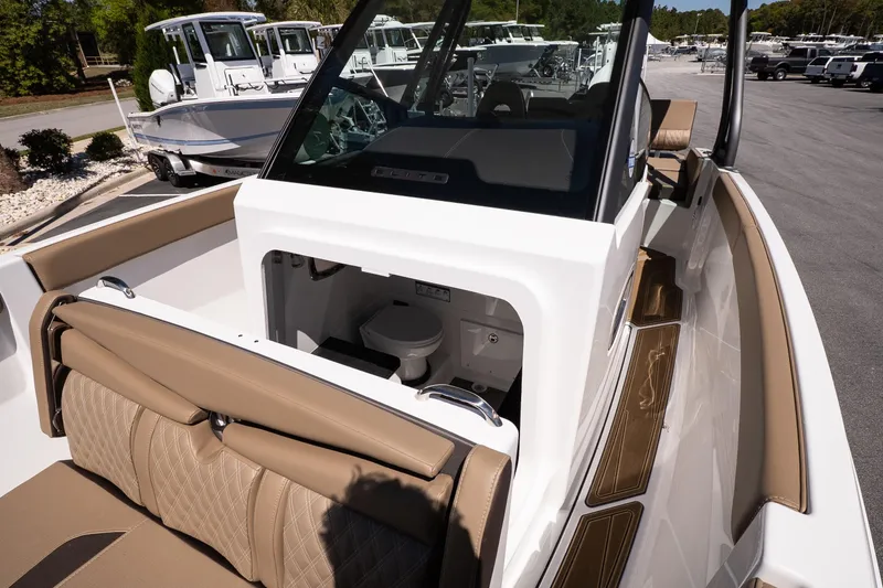 Slide: The Image of 2026 Monterey Elite 25 OB boat interior with seating and compact restroom. - 16