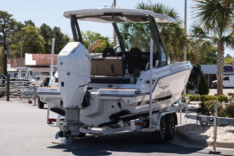 Slide: The Image of 2026 Monterey Elite 25 OB boat on trailer, parked outdoors with palm trees in background. - 6
