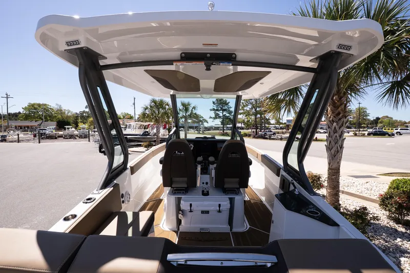 Slide: The Image of 2026 Monterey Elite 25 OB boat interior with seating and helm, parked outdoors. - 7