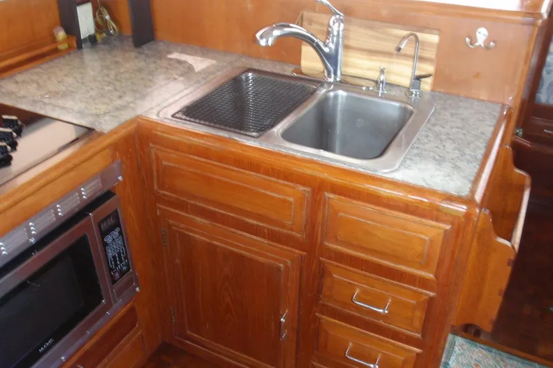 Slide: The Image of 1985 Ocean Alexander yacht kitchen with wooden cabinets, stainless steel sink, and microwave. - 49