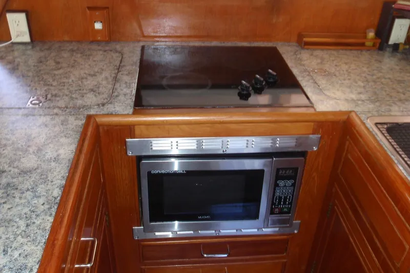 Slide: The Image of 1985 Ocean Alexander yacht kitchen with microwave and stovetop, featuring wood cabinetry and granite countertops. - 50