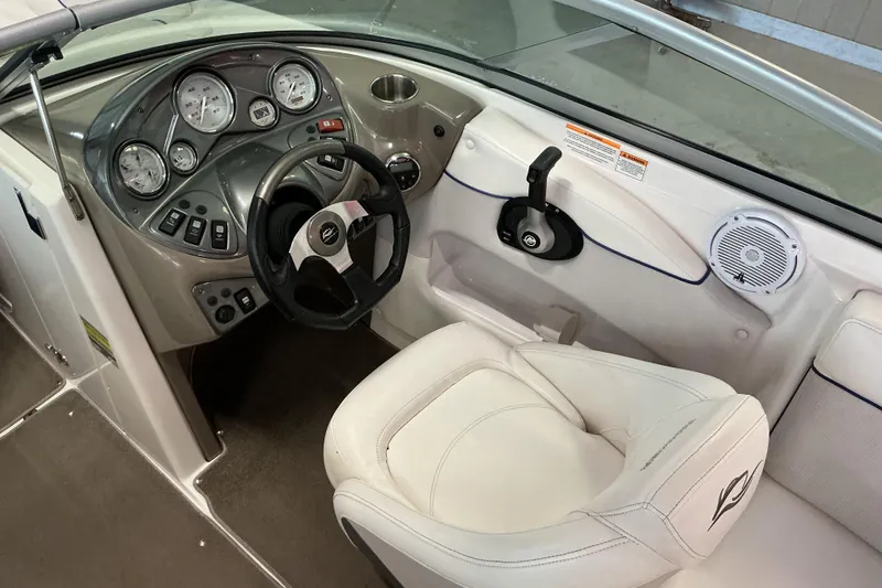 Slide: The Image of 2008 Rinker 226 Captiva Bowrider cockpit with steering wheel, gauges, and white seating. - 13